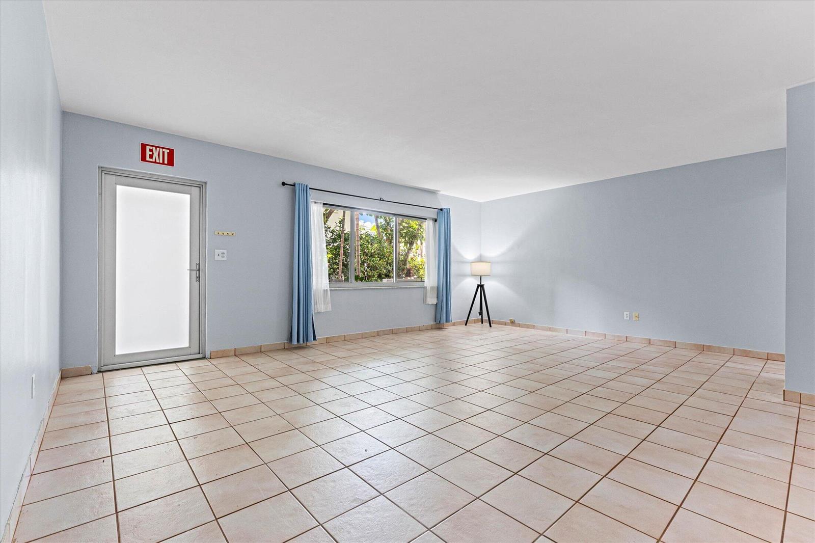 An empty room with light blue walls, beige tile flooring, and a glass exit door — 1145 101 St # 1, Bay Harbor Islands FL 33154, BAY HARBOR ISLANDS, FL