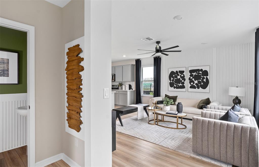 A living room with a slatted accent wall, neutral furniture, and an adjacent kitchen area — 2142 MOSSY VINE AVENUE, ST CLOUD, FL