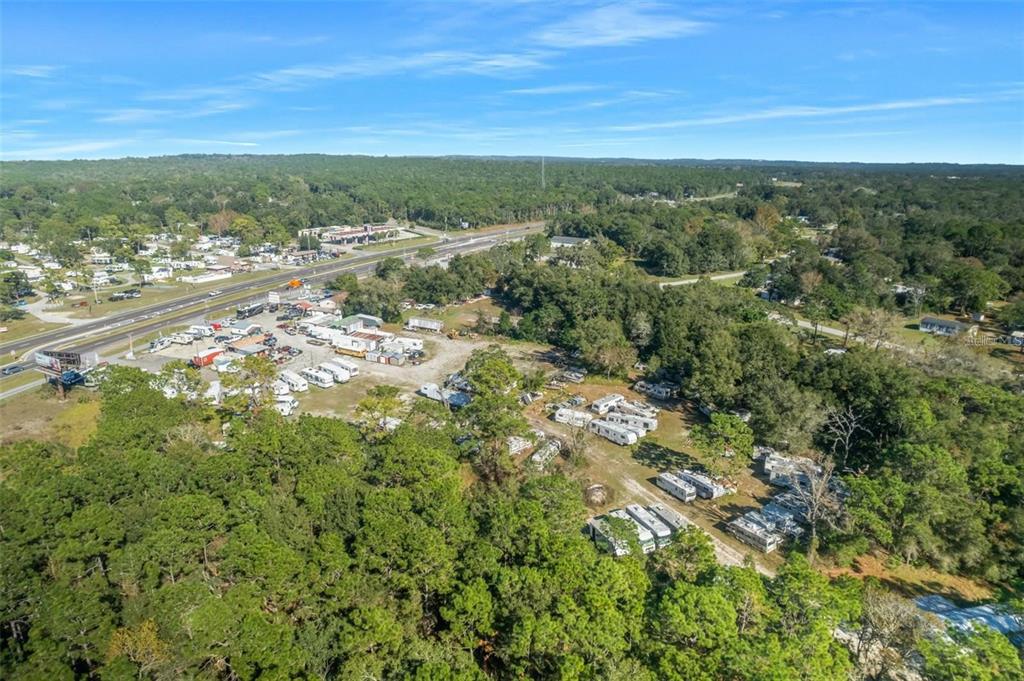 An aerial view shows a large, wooded lot with numerous parked RVs and trailers — 16076 CORTEZ BOULEVARD, BROOKSVILLE, FL