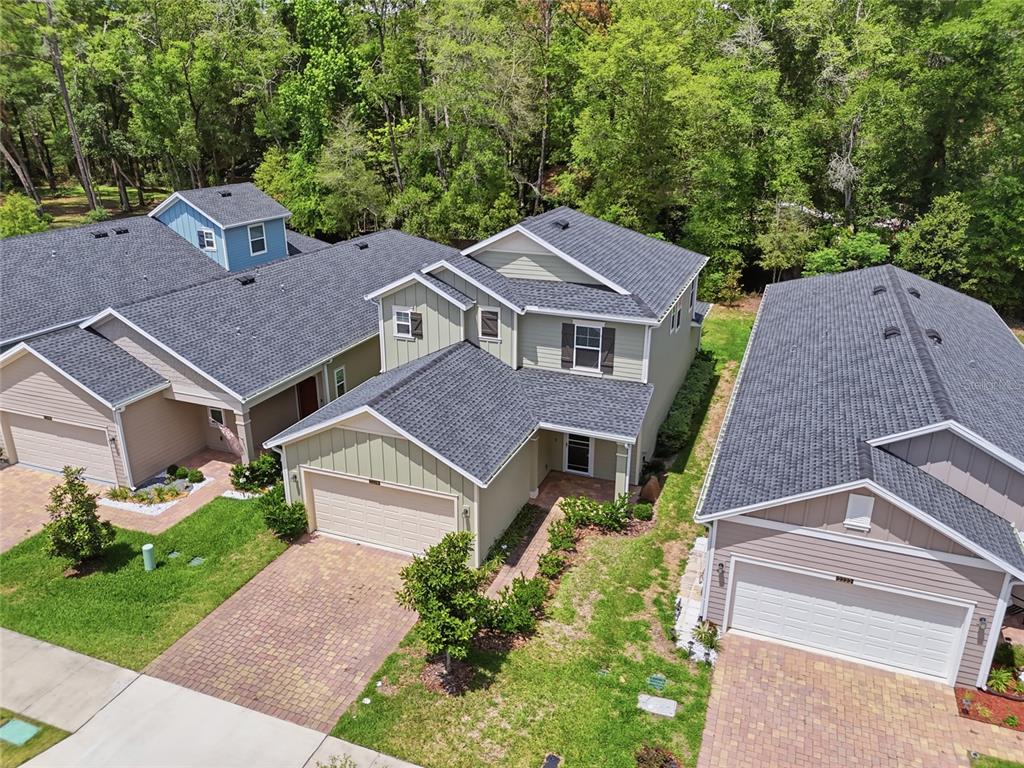 An aerial view shows three suburban houses with gray shingled roofs and paved driveways — 2208 NW 89TH WAY, GAINESVILLE, FL