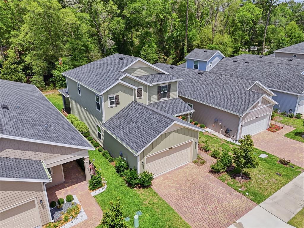 An aerial view shows a two-story green house with a paved driveway and shingled roof — 2208 NW 89TH WAY, GAINESVILLE, FL
