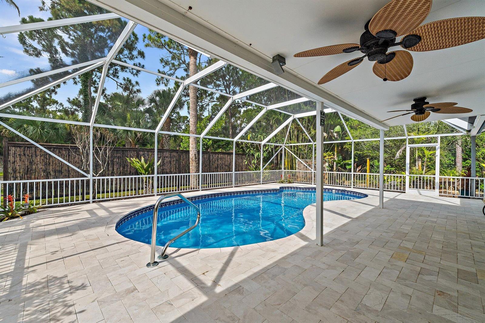 A screened-in patio features a kidney-shaped swimming pool, stone pavers, and two ceiling fans — 11480 150th Court N, FL 33478, FL