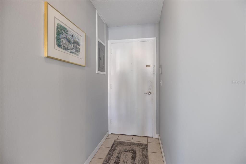 A small entryway features a white door, light gray walls, and tiled flooring — 708 TAMIAMI TRAIL S UNIT 209, VENICE, FL