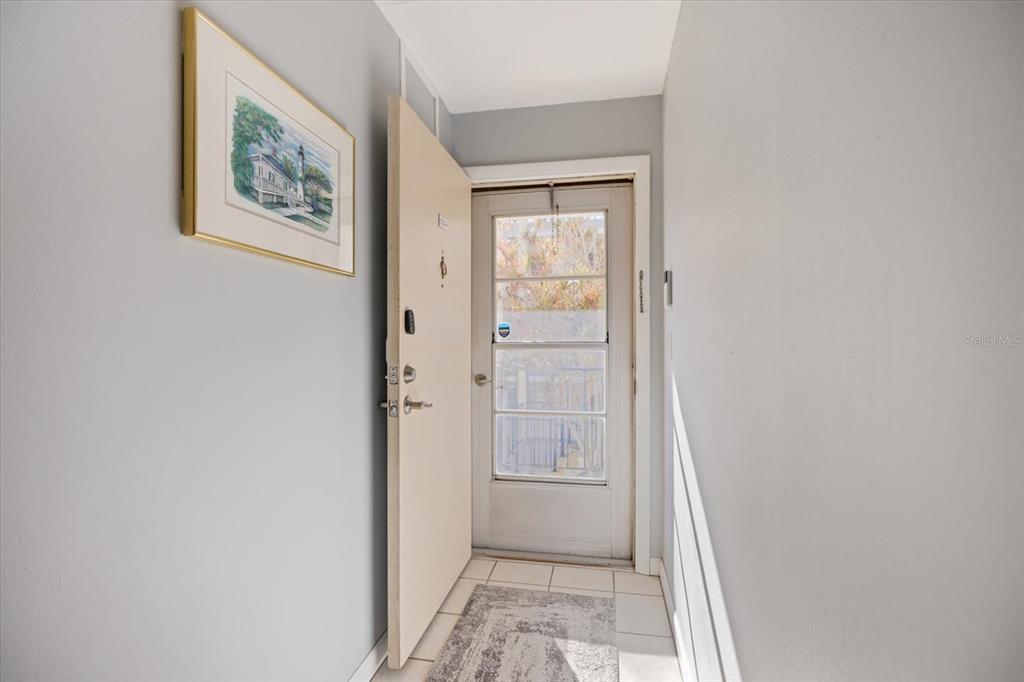 An entryway features a white door, tiled floor, and a framed lighthouse print on the wall — 708 TAMIAMI TRAIL S UNIT 209, VENICE, FL