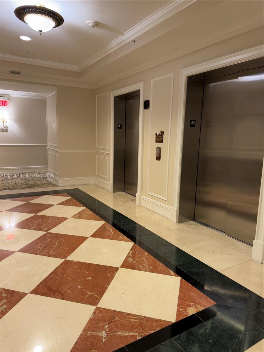 An elevator lobby features a checkered marble floor, two stainless steel elevators, and beige walls — 16100 Emerald Estates Dr # 281, Weston FL 33331, WESTON, FL
