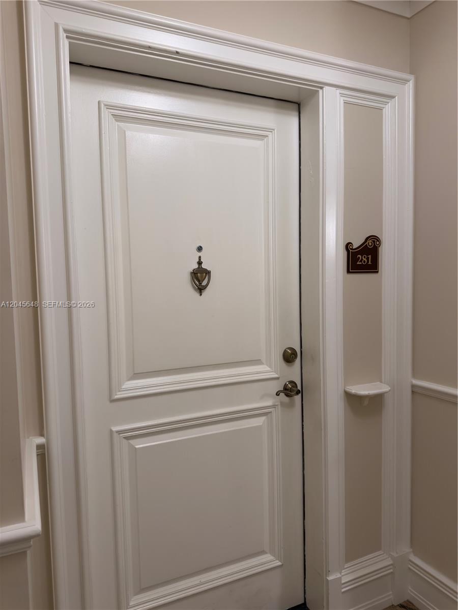 A white door with a brass knocker and a small shelf features the number 281 — 16100 Emerald Estates Dr # 281, Weston FL 33331, WESTON, FL