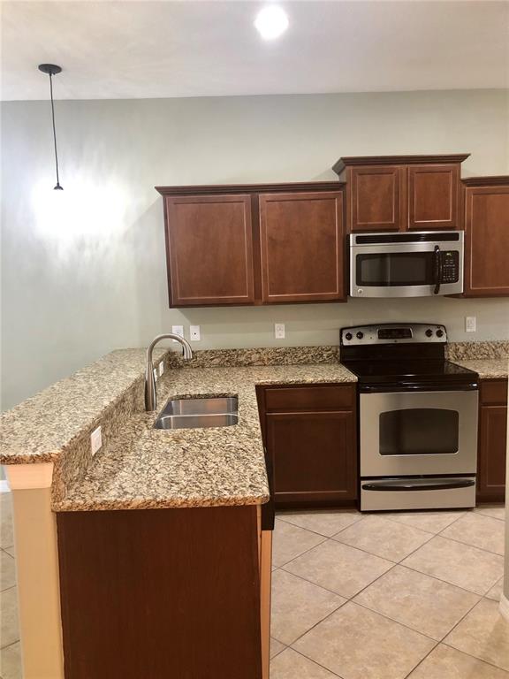 A kitchen features dark wood cabinets, granite countertops, and stainless steel appliances — 8541 BRUSHLEAF WAY, TAMPA, FL
