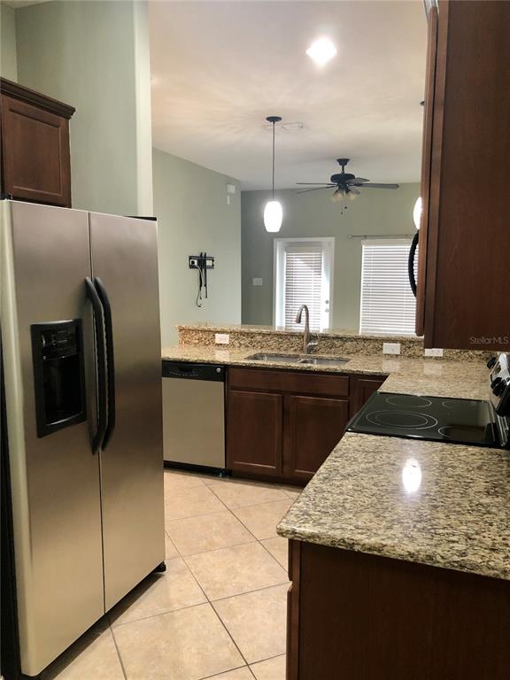 A kitchen features stainless steel appliances, granite countertops, dark wood cabinets, and tile flooring — 8541 BRUSHLEAF WAY, TAMPA, FL