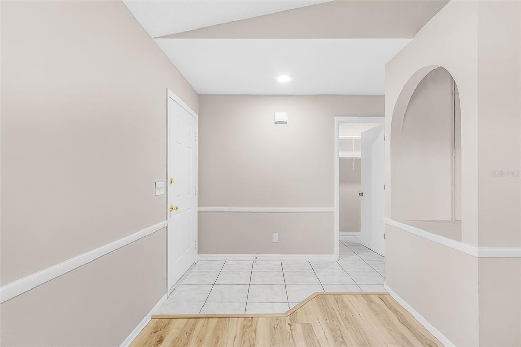 An entryway features white tile flooring, beige walls with chair rail molding, and an arched opening — 1128 INVERNESS STREET, PORT CHARLOTTE, FL