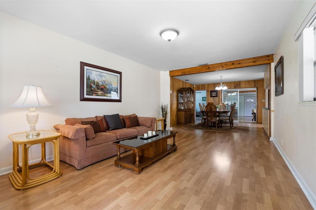 A living room with wood-look flooring, a brown sofa, and an adjacent dining area — 1520 S RICHARD AVENUE, TAMPA, FL