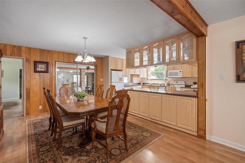 A dining area with wood-paneled walls sits adjacent to a kitchen with light wood cabinets — 1520 S RICHARD AVENUE, TAMPA, FL