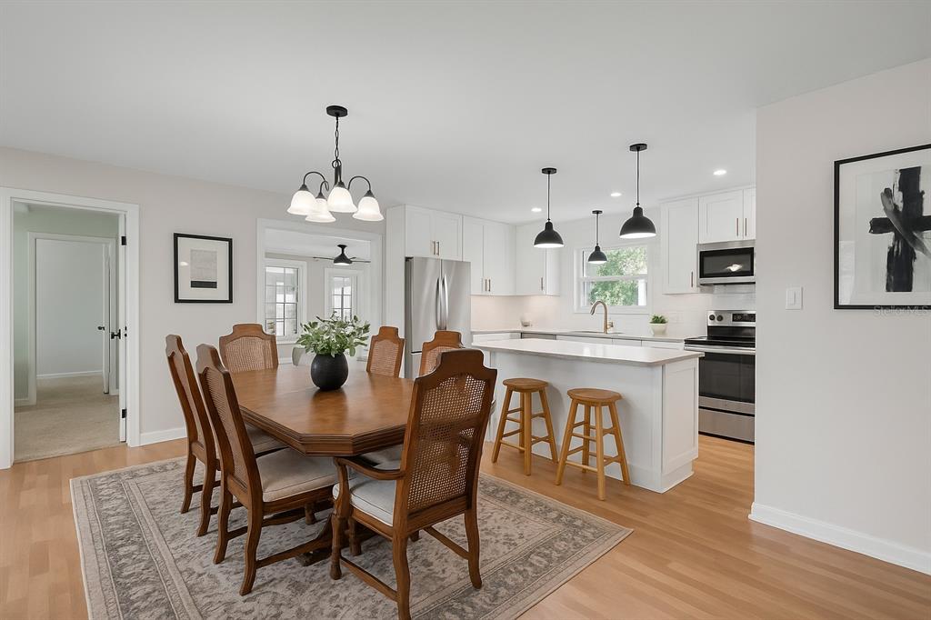 A dining area with a wooden table and chairs adjacent to a white modern kitchen — 1520 S RICHARD AVENUE, TAMPA, FL