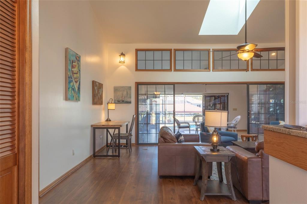 A living room with wood floors, a skylight, and sliding glass doors leading to a patio — 27 CHERRYTREE COURT, PALM COAST, FL