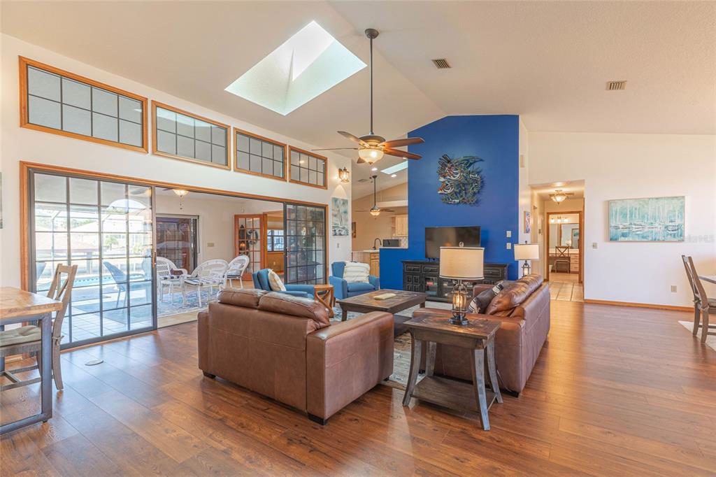A living room features a blue accent wall, vaulted ceilings with a skylight, and flooring — 27 CHERRYTREE COURT, PALM COAST, FL