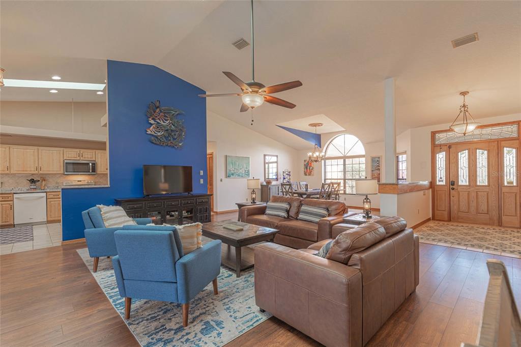A living room with a blue accent wall, brown leather sofa, and two blue armchairs — 27 CHERRYTREE COURT, PALM COAST, FL