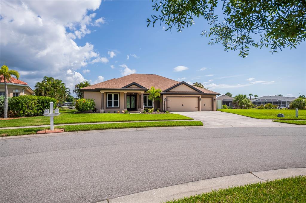 A single-story house with a tan exterior, a brown roof, and a three-car garage — 8730 MYSTIC CIRCLE, NORTH PORT, FL