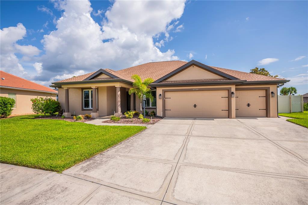 A single-story house with a tan exterior, a three-car garage, and a concrete driveway — 8730 MYSTIC CIRCLE, NORTH PORT, FL