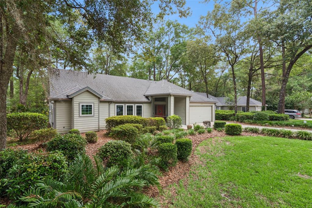 A single-story house with light-colored siding, a shingled roof, and a landscaped front yard — 10525 SW 55TH PLACE, GAINESVILLE, FL
