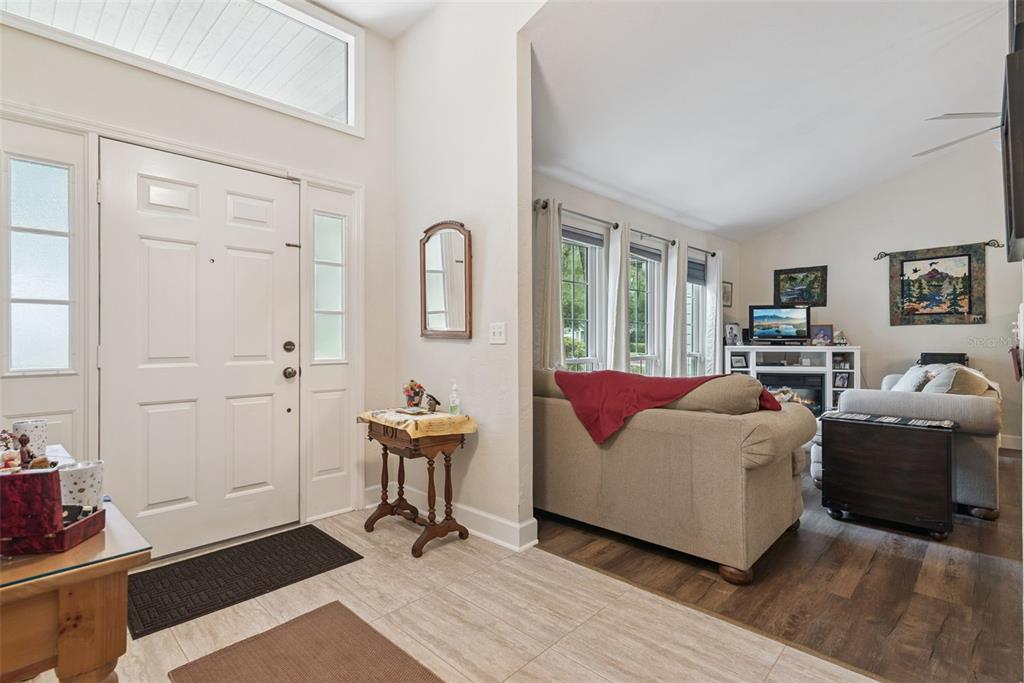 An entryway with tile flooring leads into a living room featuring wood-look floors and furniture — 10525 SW 55TH PLACE, GAINESVILLE, FL