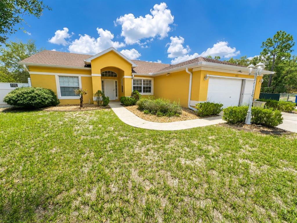 A yellow single-story house with a white garage door and a concrete walkway — 14244 MULKERIN DRIVE, WEEKI WACHEE, FL