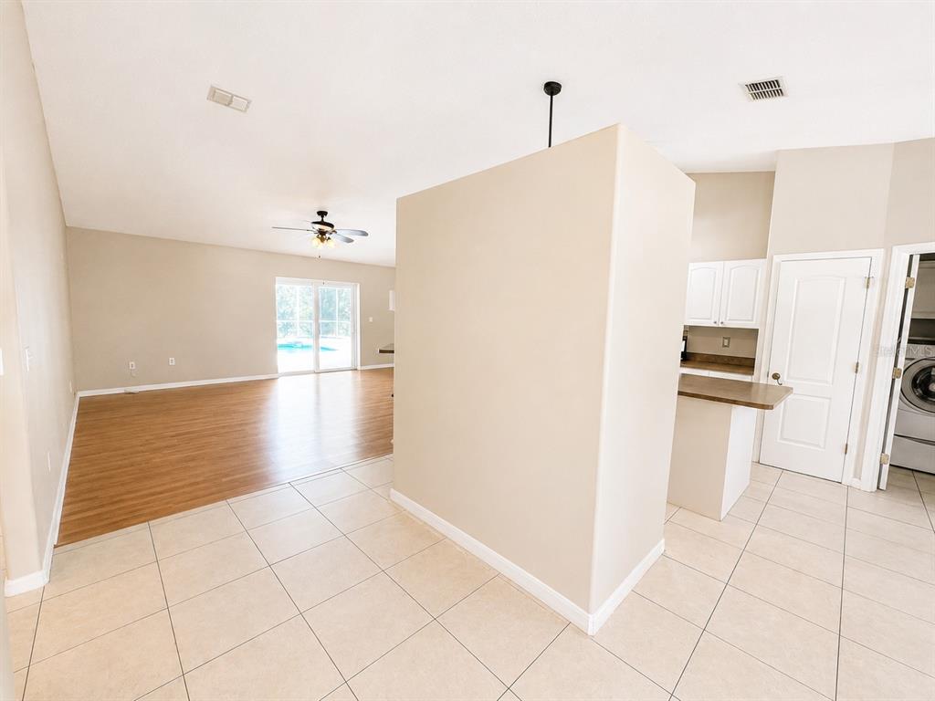 An open-concept living area features tile flooring, a central partition wall, and a wood-floored room — 14244 MULKERIN DRIVE, WEEKI WACHEE, FL