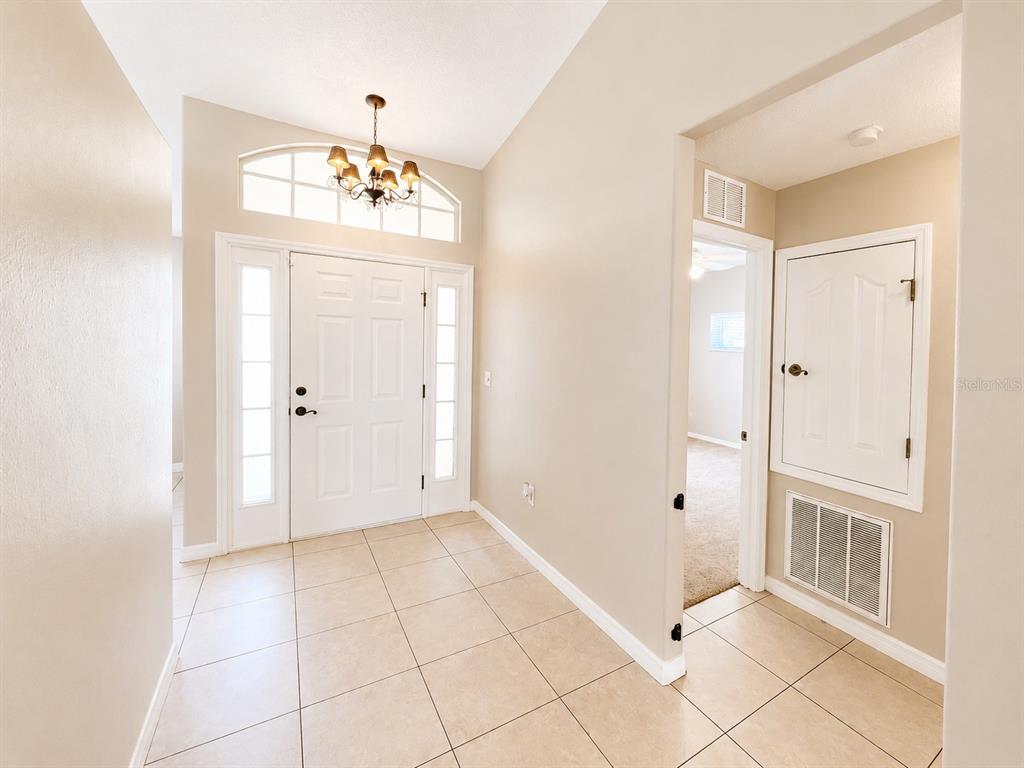 An entryway with tile flooring, a white front door, and a chandelier — 14244 MULKERIN DRIVE, WEEKI WACHEE, FL