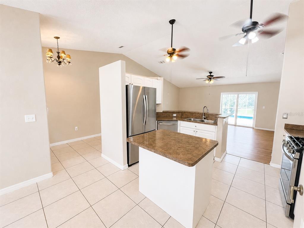 A kitchen with white cabinets, stainless steel appliances, a center island, and tile flooring — 14244 MULKERIN DRIVE, WEEKI WACHEE, FL