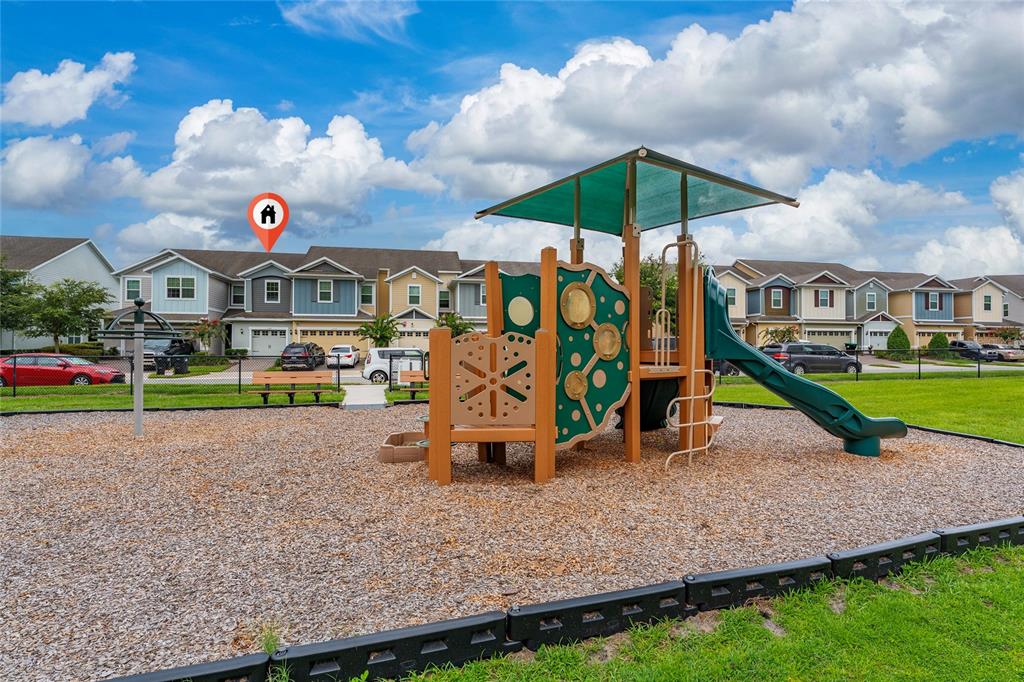 A playground with a slide and climbing structure sits in front of a row of townhomes — 2342 SEDGE GRASS WAY, ORLANDO, FL