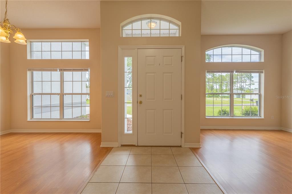 An entryway features a tiled floor, a white front door with sidelights, and large windows — 13 ZINNIA TRAIL, PALM COAST, FL
