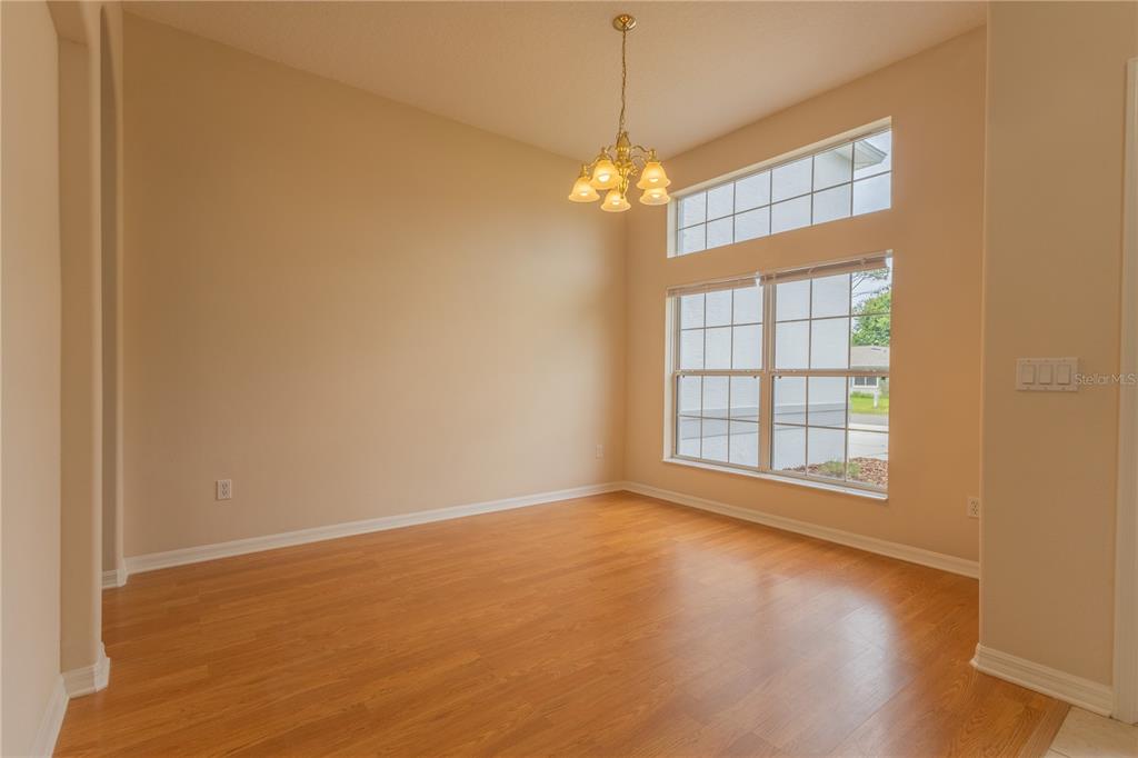 An empty dining room with wood-look flooring, a chandelier, and large windows — 13 ZINNIA TRAIL, PALM COAST, FL