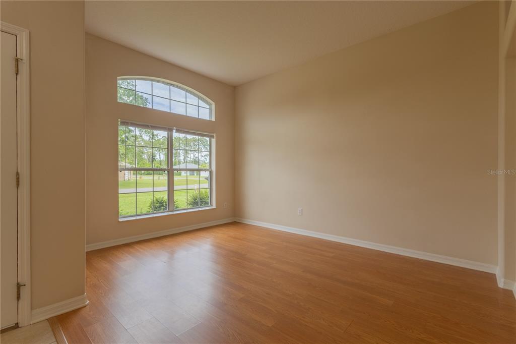 An empty room with light-colored walls, wood-look flooring, and a large arched window — 13 ZINNIA TRAIL, PALM COAST, FL