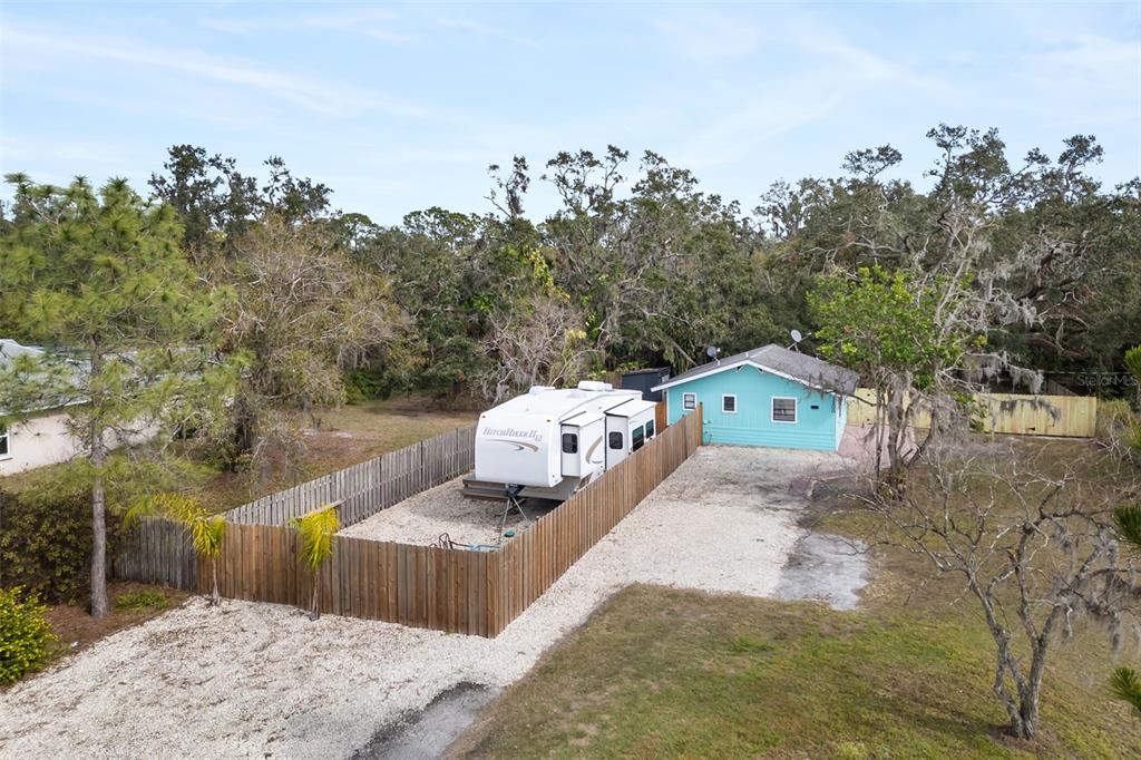 An aerial view shows a turquoise house with a fenced-in RV parked on a gravel lot — 3200 TOBERO LANE, SARASOTA, FL