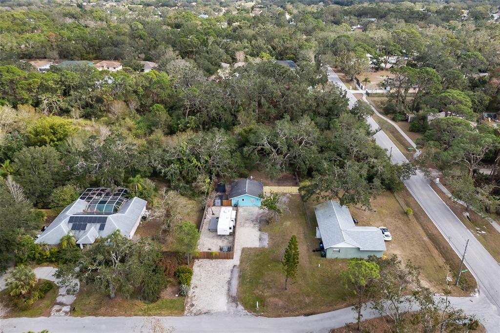 An aerial view shows three houses surrounded by dense trees near a paved road — 3200 TOBERO LANE, SARASOTA, FL