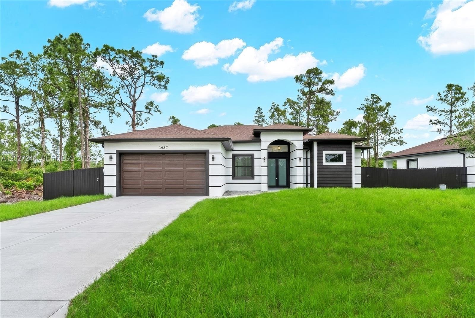 A single-story house with a white and dark brown exterior, a garage, and a lawn — 1047 E Merry St, Lehigh Acres FL 33974, LEHIGH ACRES, FL