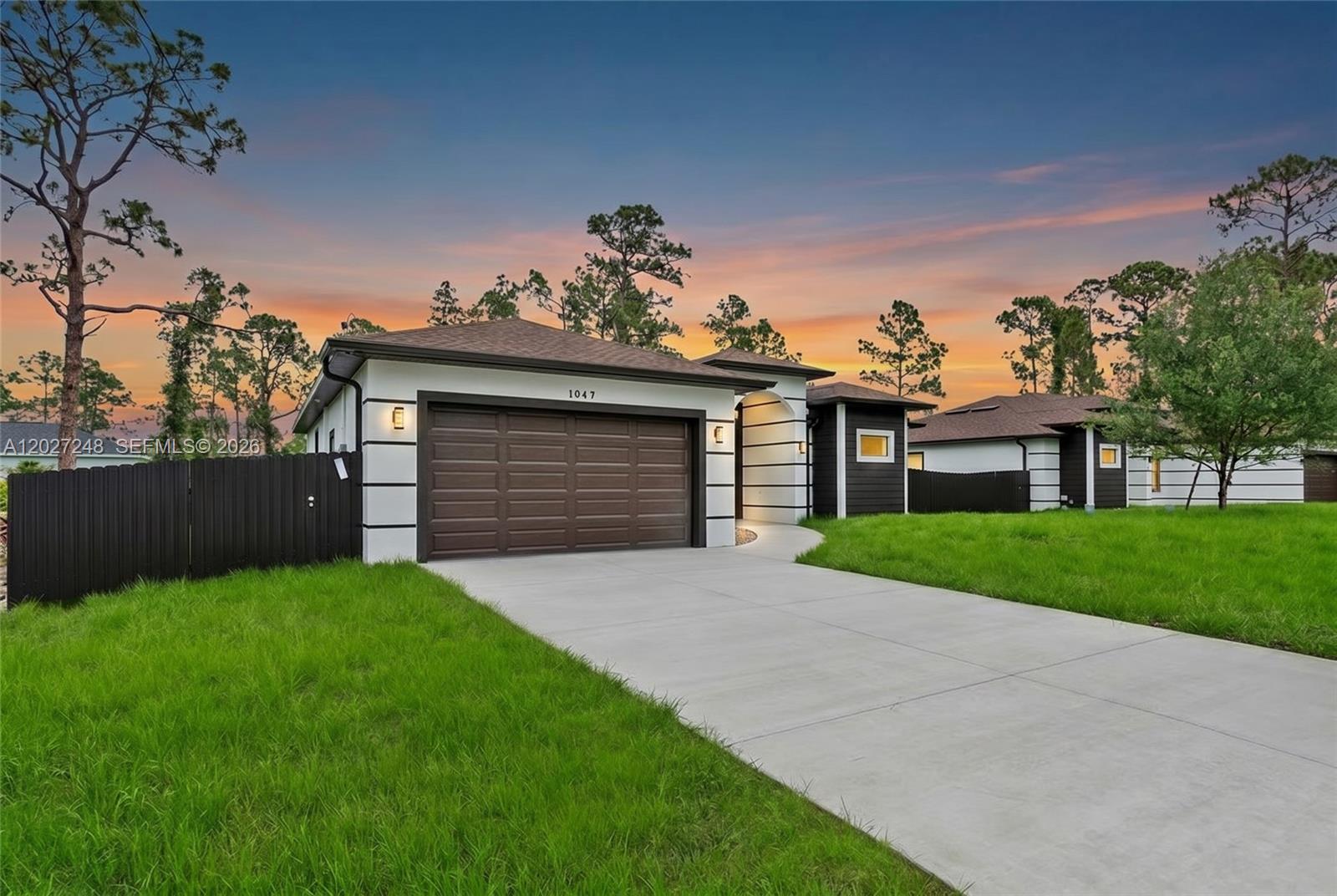 A modern single-story house with a brown garage door and white walls with black accents — 1047 E Merry St, Lehigh Acres FL 33974, LEHIGH ACRES, FL