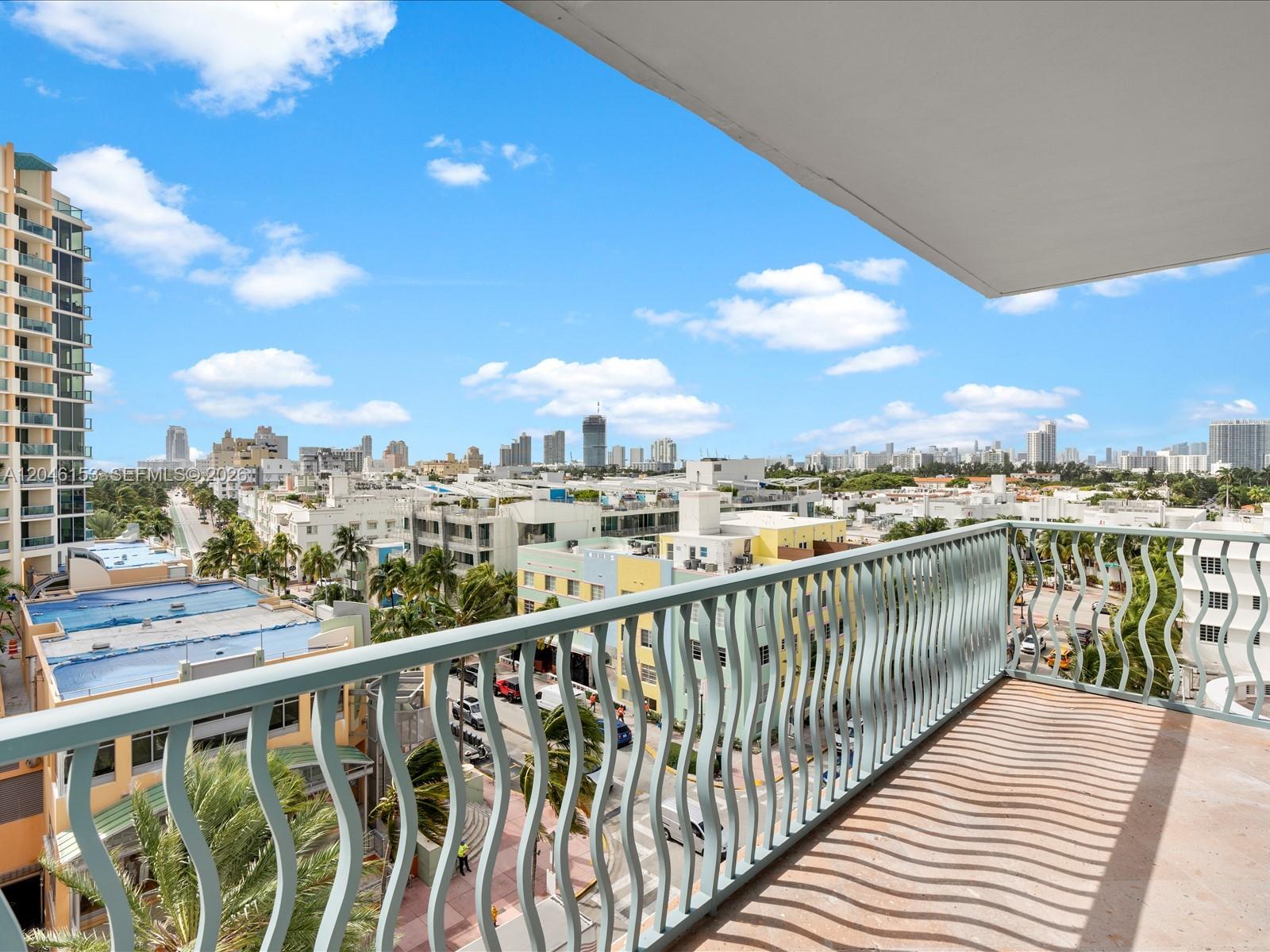 A balcony with a light blue metal railing overlooks a city street and skyline — 1500 Ocean Dr # 708, Miami Beach FL 33139, MIAMI BEACH, FL
