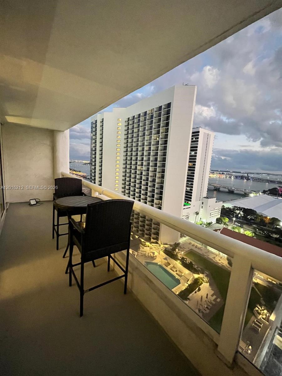 A balcony with a small table and chairs overlooks a pool and city skyline — 1717 N Bayshore Dr # 2453, Miami FL 33132, MIAMI, FL