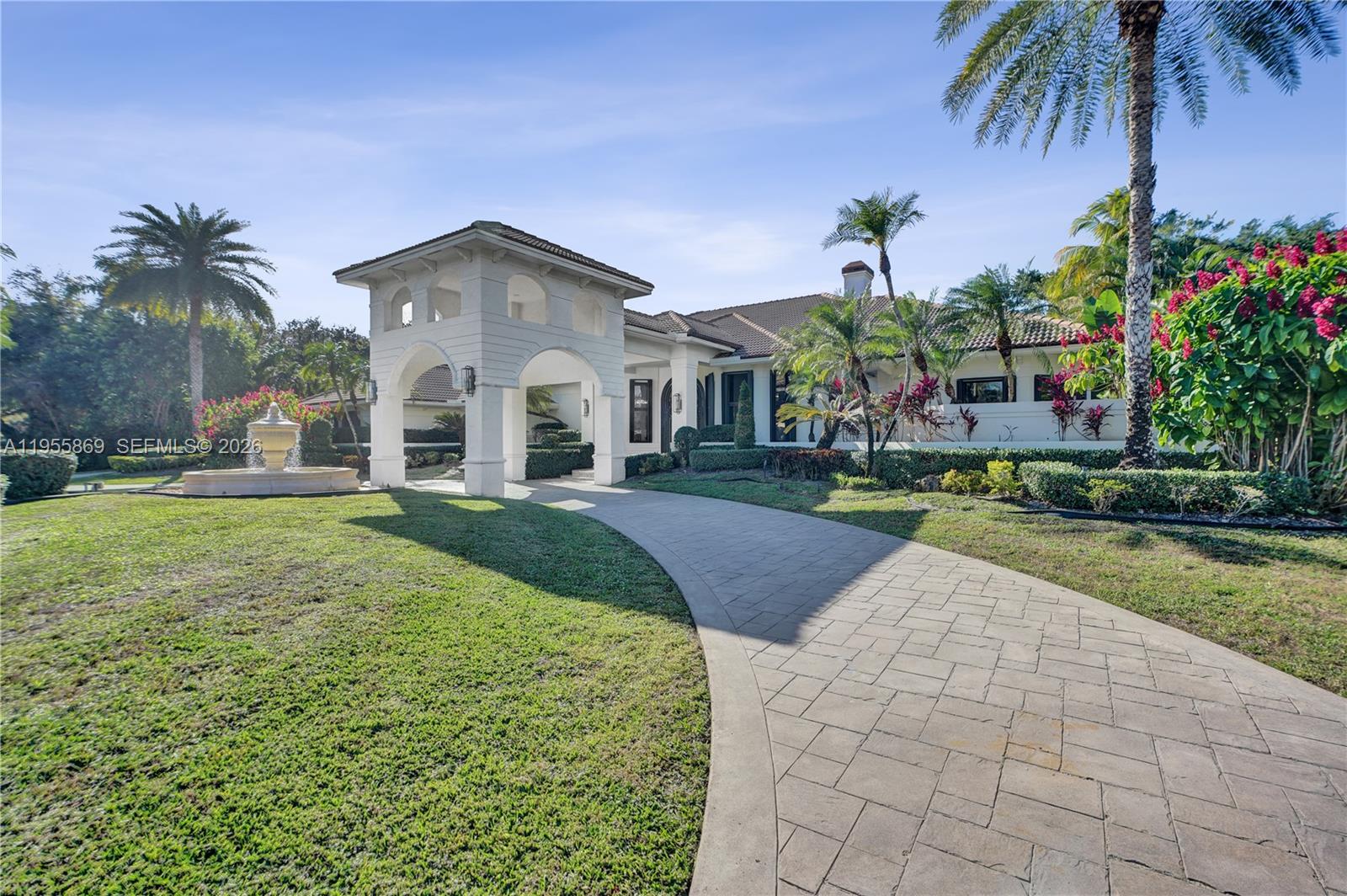 A paved driveway leads to a white house with a covered porte-cochère and a fountain — 3175 Hunter Road, Weston FL 33331, WESTON, FL