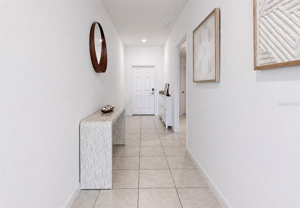 A bright hallway features light tile flooring, a console table, and wall-mounted artwork — 13265 GREAT PLAINS DRIVE, RIVERVIEW, FL