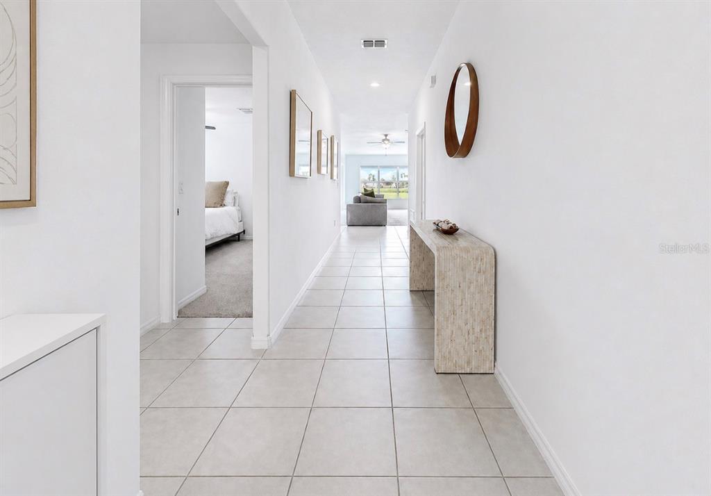 A bright hallway with light tile flooring leads to a living area with a sofa — 13265 GREAT PLAINS DRIVE, RIVERVIEW, FL
