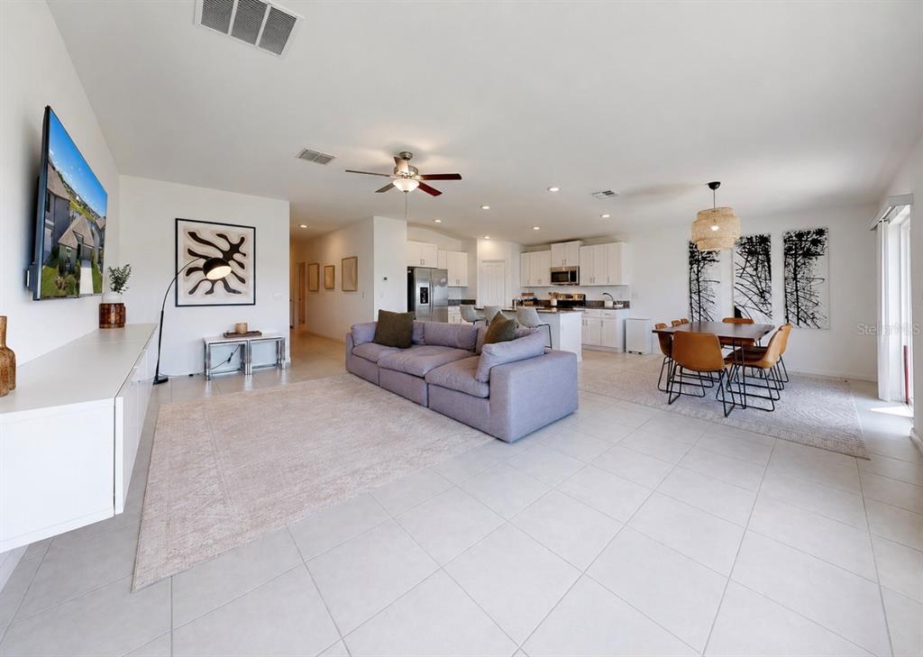 An open-concept living and dining area features tile flooring, a gray sectional, and white cabinetry — 13265 GREAT PLAINS DRIVE, RIVERVIEW, FL