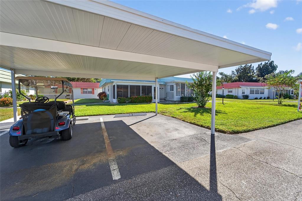 A covered carport with a golf cart sits in front of a single-story residential home — 1802 BEDFORD LANE UNIT 12, SUN CITY CENTER, FL