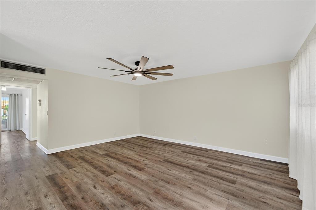 An empty room with light-colored walls, wood-look flooring, and a ceiling fan — 1802 BEDFORD LANE UNIT 12, SUN CITY CENTER, FL