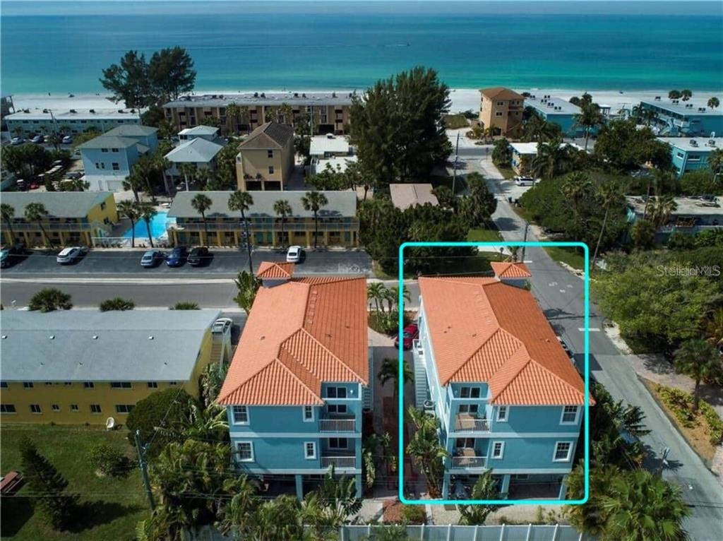 An aerial view shows two blue, multi-story buildings with orange tile roofs near the beach — 2319 AVENUE C UNIT 200, BRADENTON BEACH, FL