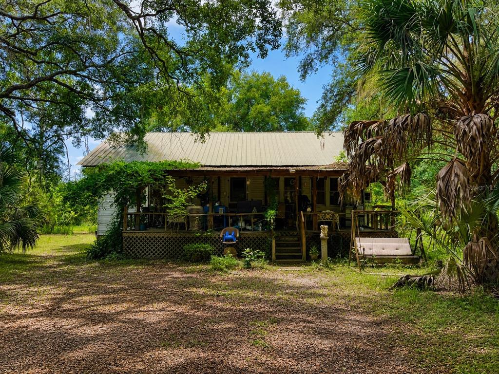A rustic, single-story house with a metal roof and a large, covered front porch — 39 NE 526TH STREET, OLD TOWN, FL