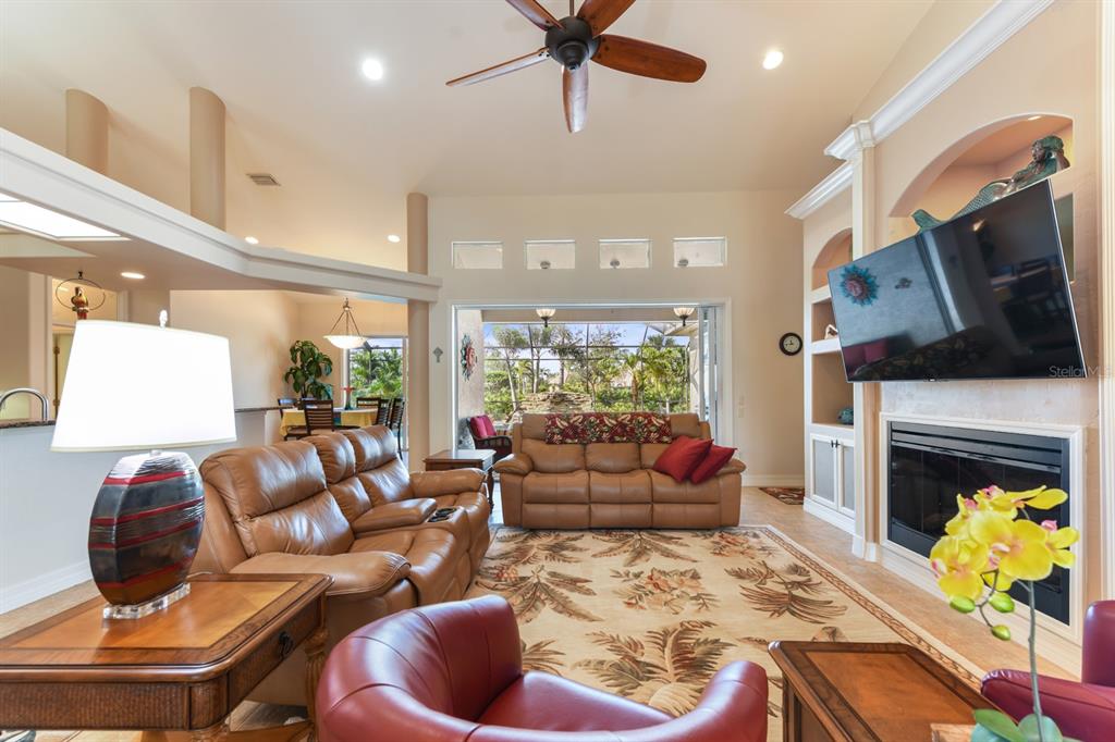 A living room features leather sofas, a fireplace with a mounted television, and outdoor views — 4911 LINKSIDE DRIVE, PUNTA GORDA, FL