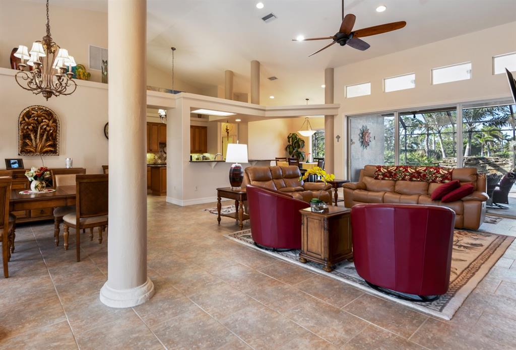 A spacious open-concept living and dining area features tile floors, columns, and large sliding doors — 4911 LINKSIDE DRIVE, PUNTA GORDA, FL