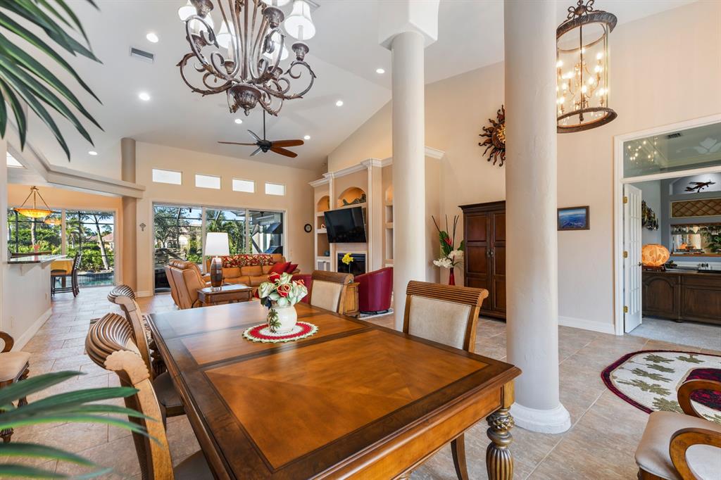 A dining room with a wooden table, chandelier, and columns opening into a living area — 4911 LINKSIDE DRIVE, PUNTA GORDA, FL