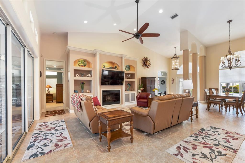A spacious living room features tile floors, a fireplace with built-in shelving, and vaulted ceilings — 4911 LINKSIDE DRIVE, PUNTA GORDA, FL