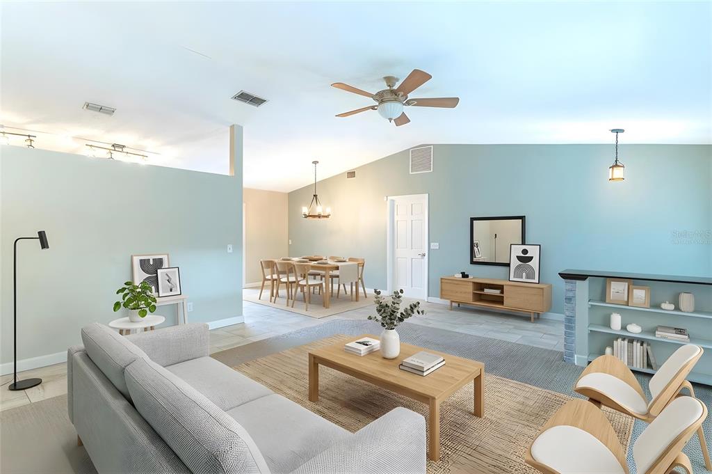 A living room with light blue walls, a gray sofa, and an adjacent dining area — 715 S LAKESIDE TERRACE, EAGLE LAKE, FL